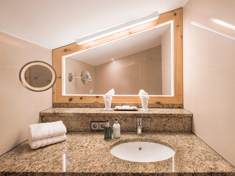 Das Badezimmer mit Granit-Waschtisch im Doppelzimmer Morgentau im Hotel Oswald mit großzügigen Granit-Waschtisch.