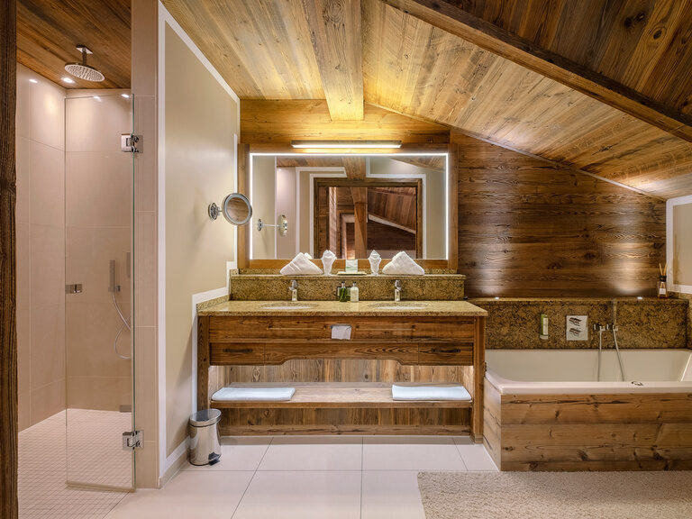 Das großzügiges Badezimmer in der Storchennest Suite mit edlen Holzdetails, moderner Regendusche und entspannender Badewanne im Hotel Oswald.