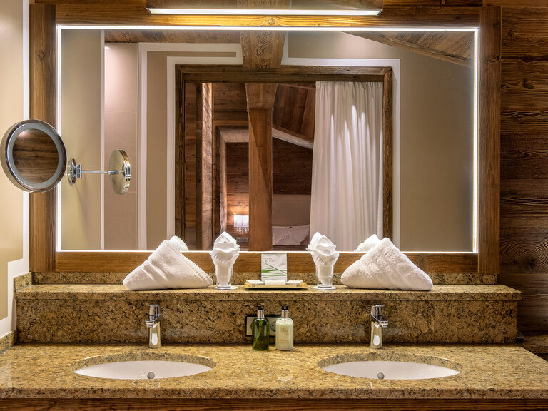 Waschtisch mit Doppelwaschbecken, edler Granitoberfläche und indirekter Spiegelbeleuchtung im Badezimmer der Suite Storchennest im Hotel Oswald.