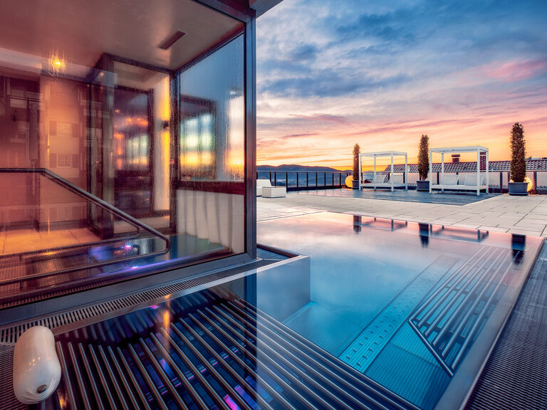 Der Infinity-Whirlpool im Hotel Oswald mit beeindruckendem Panoramablick, luxuriösen Daybeds und stimmungsvollem Sonnenuntergang für pure Entspannung.