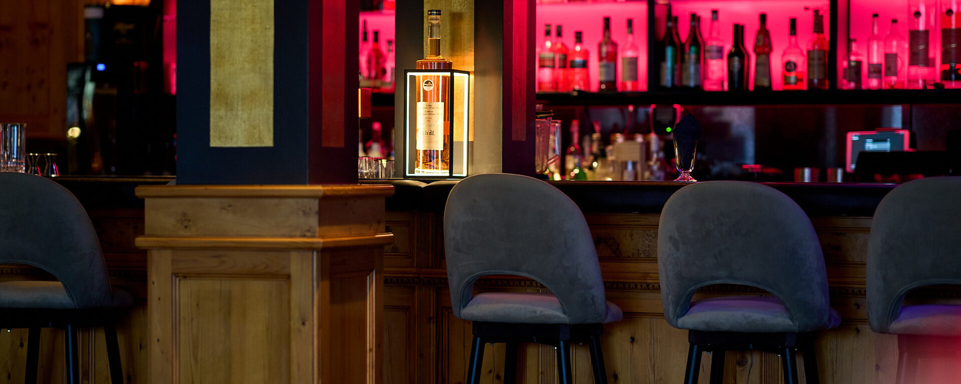 die Exklusive Bar im Hotel Oswald mit beleuchteter Spirituosenauswahl, gemütlichen Barhockern im Bayerischen Wald.