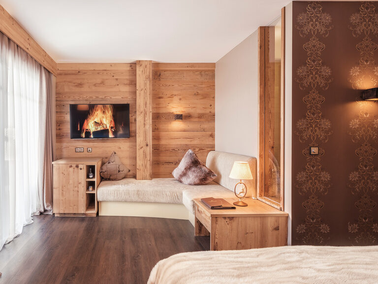 Das Doppelzimmer Hirschenstein mit Kaminfeuer-Simulation und warme Holzwände mit dezenter Beleuchtung.