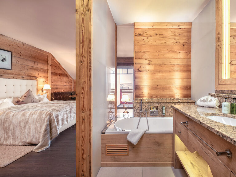 Das Doppelzimmer Hirschenstein im Hotel Oswald mit natürlichen Holzelementen, komfortablem Boxspringbett und einer gemütlichen Sitzecke.