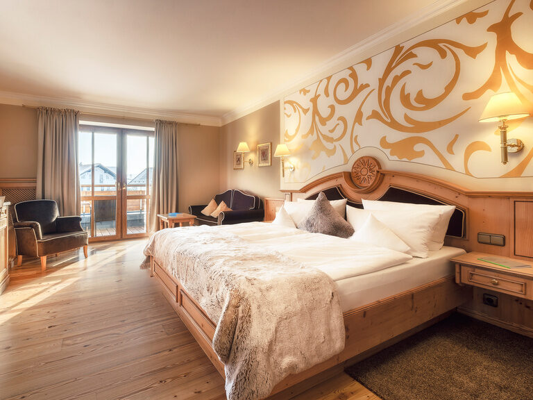 Das Doppelzimmer Landgold im Hotel Oswald im Bayerischen Wald überzeugt mit hellen Holzmöbeln, stilvoller Wandgestaltung und sonnigem Balkon.
