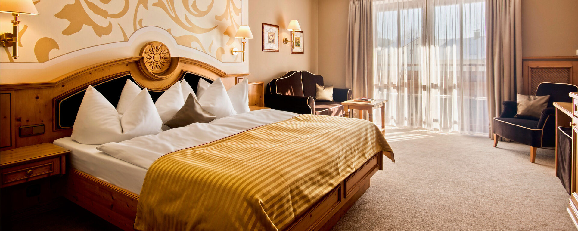 Doppelzimmer Landgold im Hotel Oswald mit kunstvoller Wandgestaltung, hochwertigem Holzbett und luxuriösen Details.