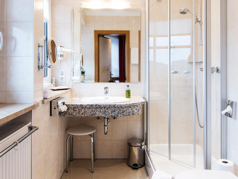 Das elegante Bad im Doppelzimmer Plus 105 mit großer Dusche, hochwertigen Fliesen und modernen Armaturen für höchsten Komfort.