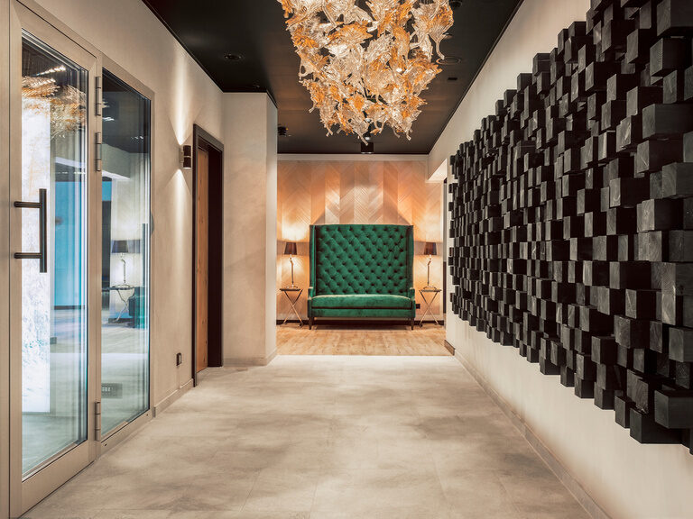 Der elegante Spa-Bereich im Hotel Oswald mit luxuriösem Kronleuchter, stilvoller Wandgestaltung und komfortabler Sitzgelegenheit.