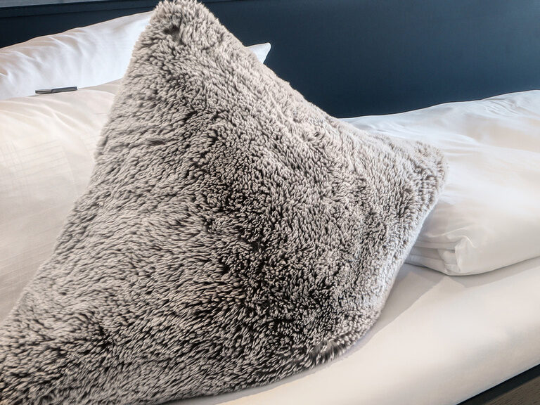 Ein flauschiges Kissen im Bett des Einzelzimmers im Hotel Oswald sorfgt für Gemütlichkeit im Bayerischen Wald.