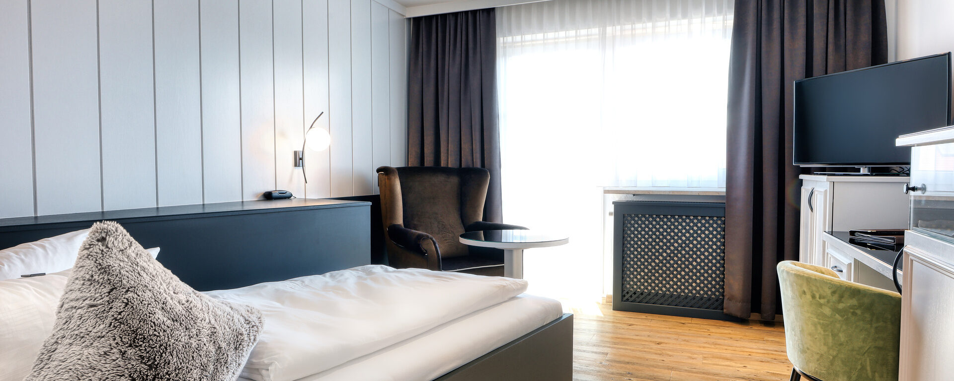 Ein gemütlich eingerichtetes Einzelzimmer im Landromantik Hotel Oswald mit einem eleganten Bett und einem funktionalen Schreibtisch.
