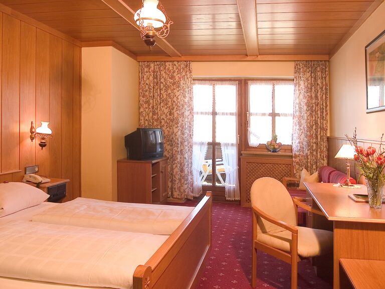 Damalige Hotelzimmer mit Holzverkleidung, Schreibtisch und Zugang zum Balkon im Hotel Oswald