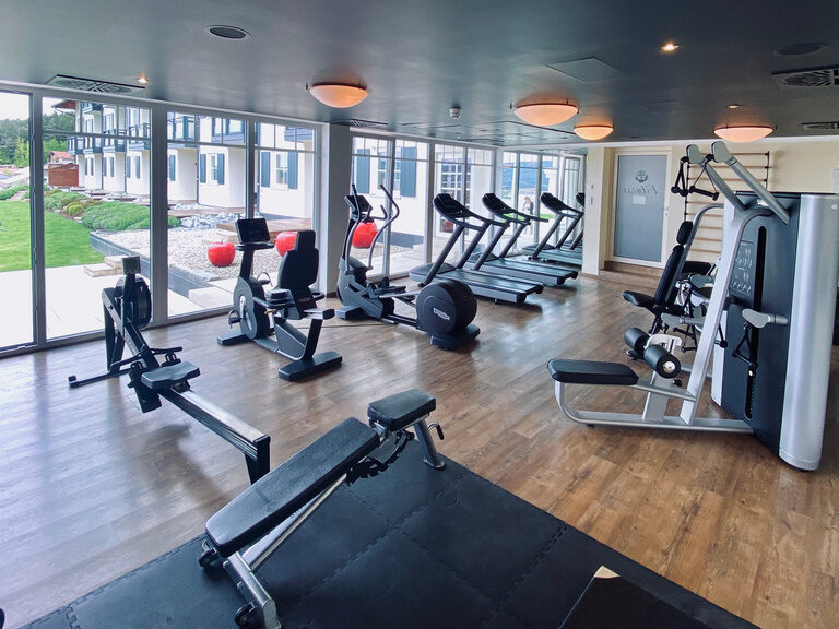 Der Fitnessraum im Landromantik Hotel Oswald mit modernen Trainingsgeräten und Blick in den Garten im Bayerischen Wald.