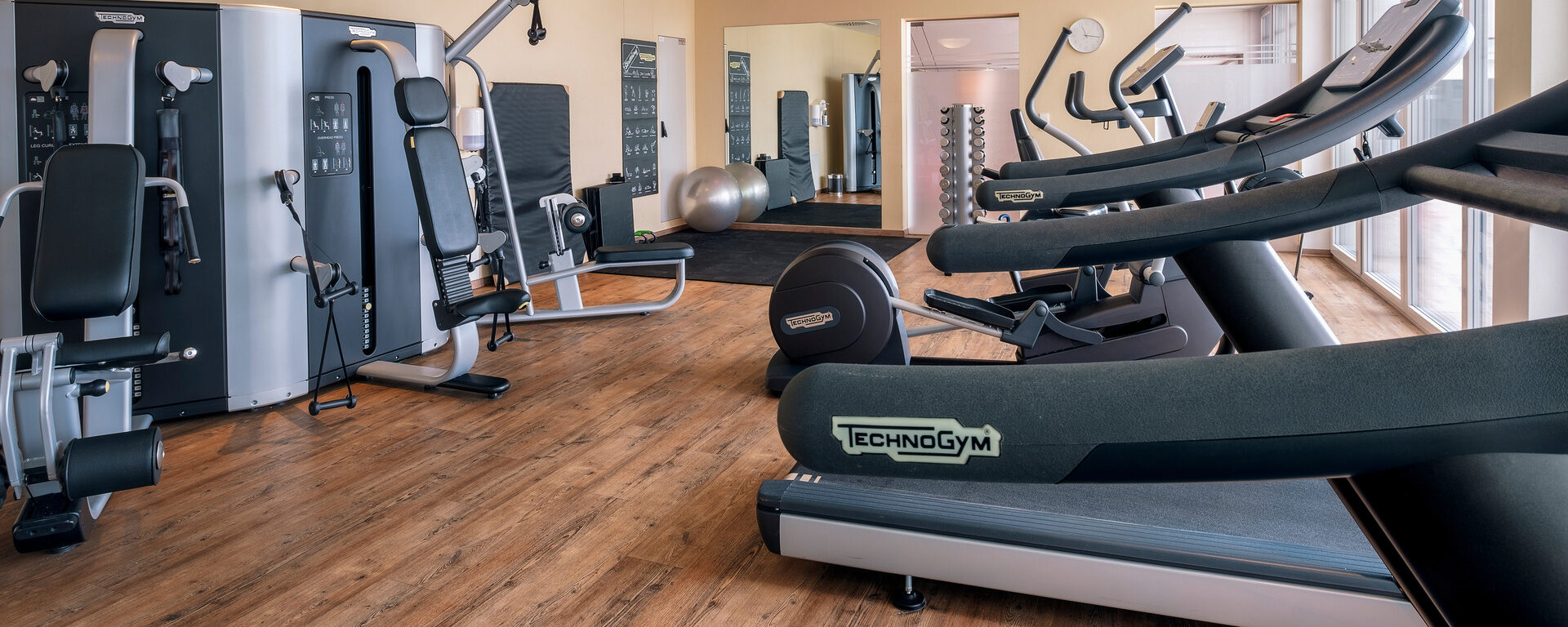 Der helle Fitnessraum im Wellnesshotel Oswald bietet moderne Trainingsgeräte und Ausblick ins Grüne.