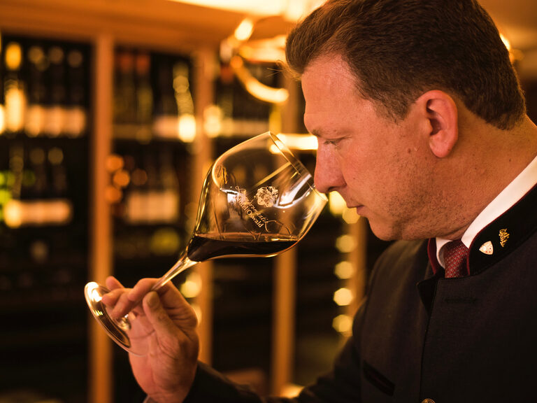 Herr Oswald, Geschäftsführer des Hotel Oswald Bayerischer Wald, verkostet Rotwein im hauseigenen Weinkeller.