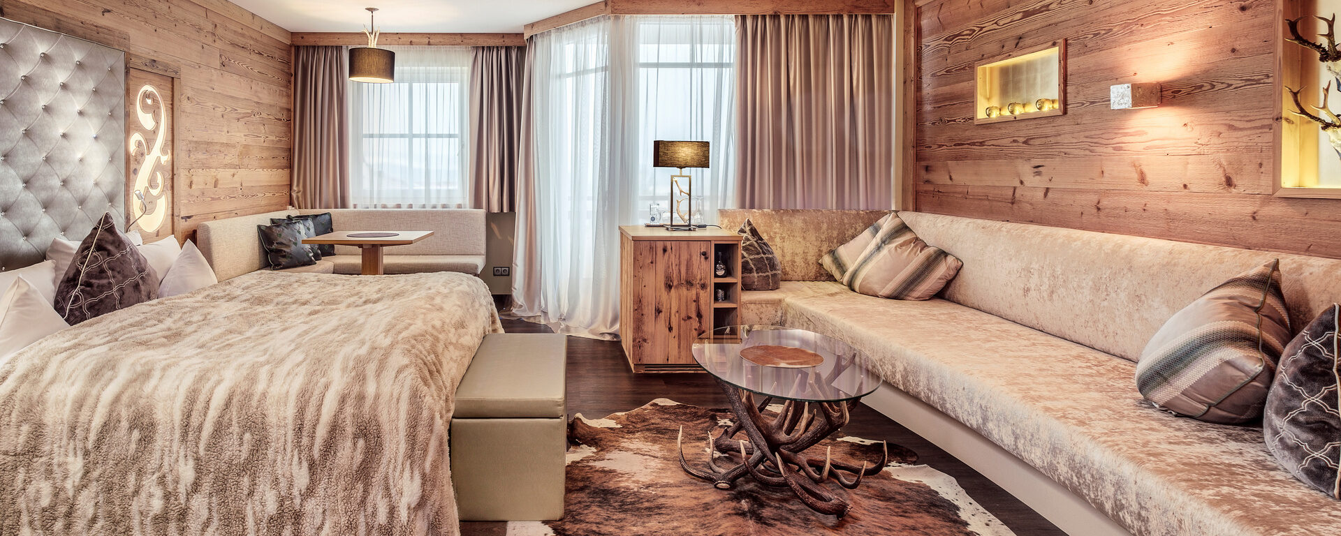 Die Hirschensteinsuite de luxe im Hotel Oswald mit rustikalen Holzwänden, stilvollem Hirschgeweih-Tisch, weicher Felldecke und gemütlicher Lounge für höchsten Komfort.