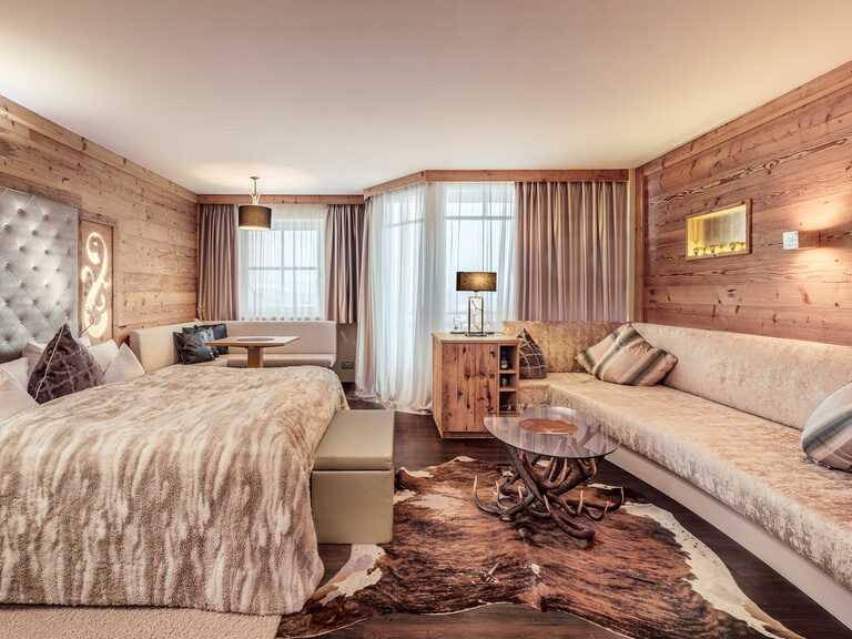 Die Hirschensteinsuite de luxe im Hotel Oswald mit rustikalen Holzwänden, stilvollem Hirschgeweih-Tisch, weicher Felldecke und gemütlicher Lounge für höchsten Komfort.