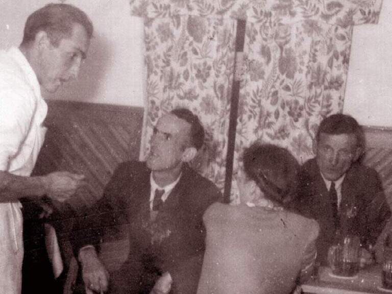 Schwarzweißfoto mit Gästen und Bedienung in der alten Gaststube des Hotel Oswald