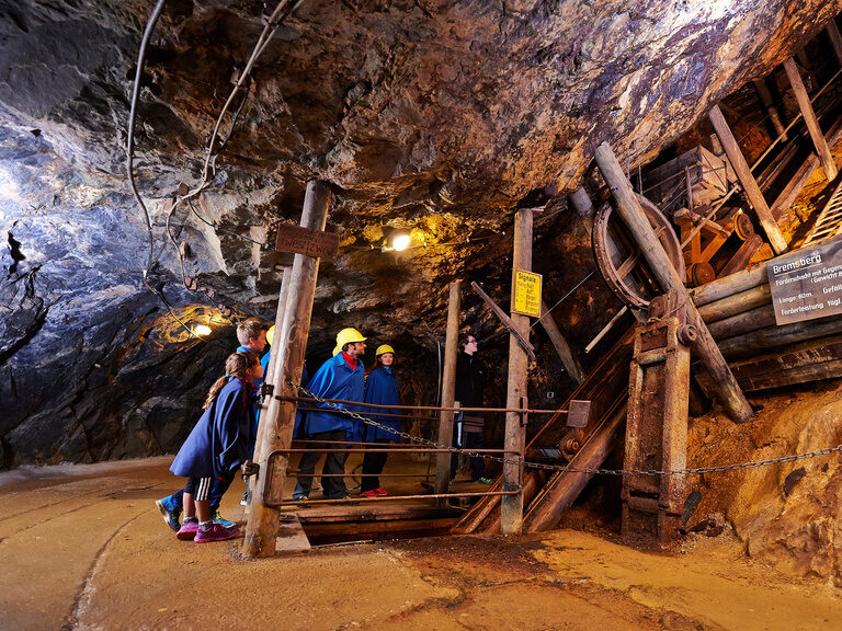 Eine Gruppe von Menschen durchquert den Tunnel des Historischen Besucherbergwerks Silberberg.