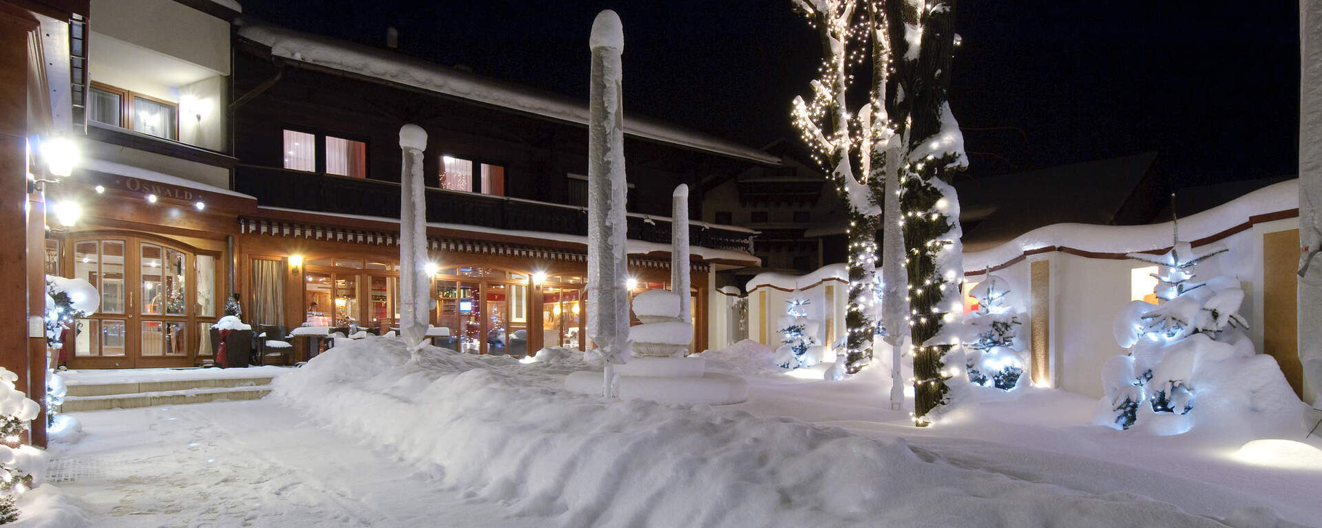 Winterlicher Eingang des Hotel Oswald Bayerischer Wald mit Lichterketten und Schnee.