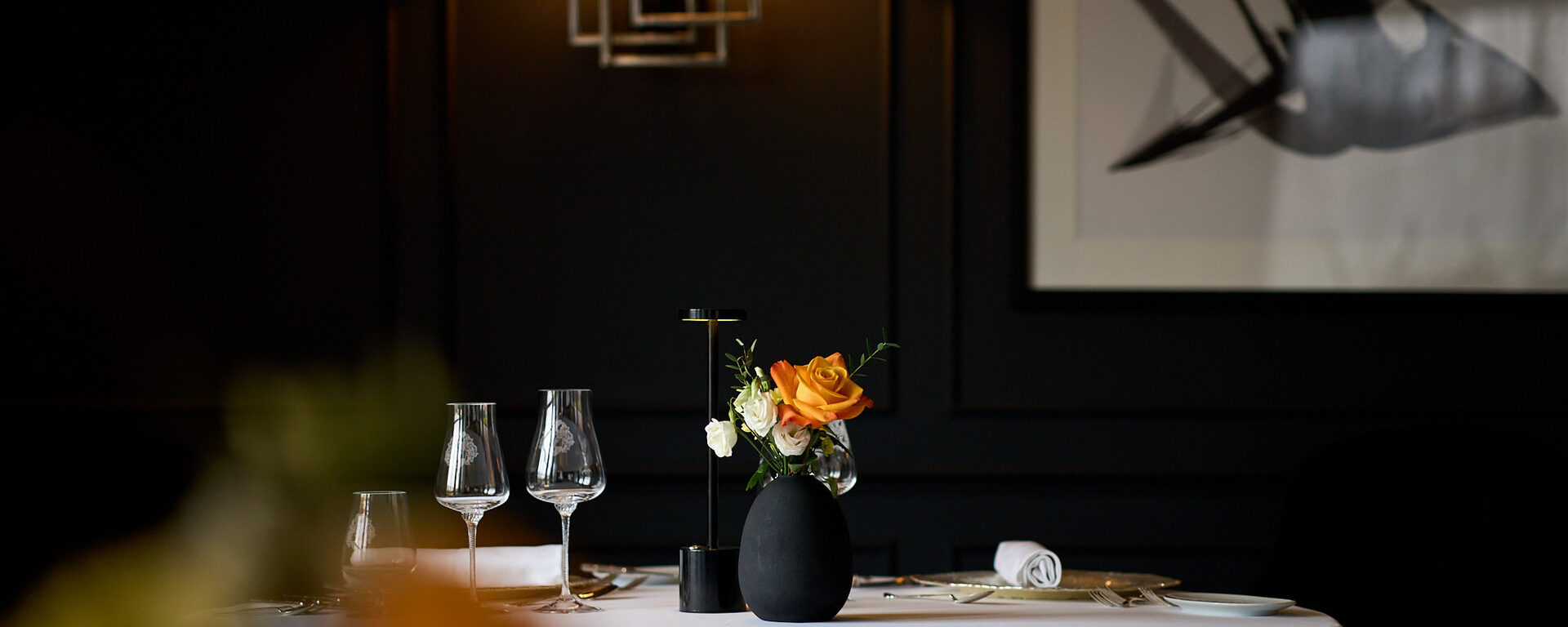 Ein stilvoll gedeckter Tisch im elegant-dunklen Fine-Dining-Bereich des Hotel Oswald.