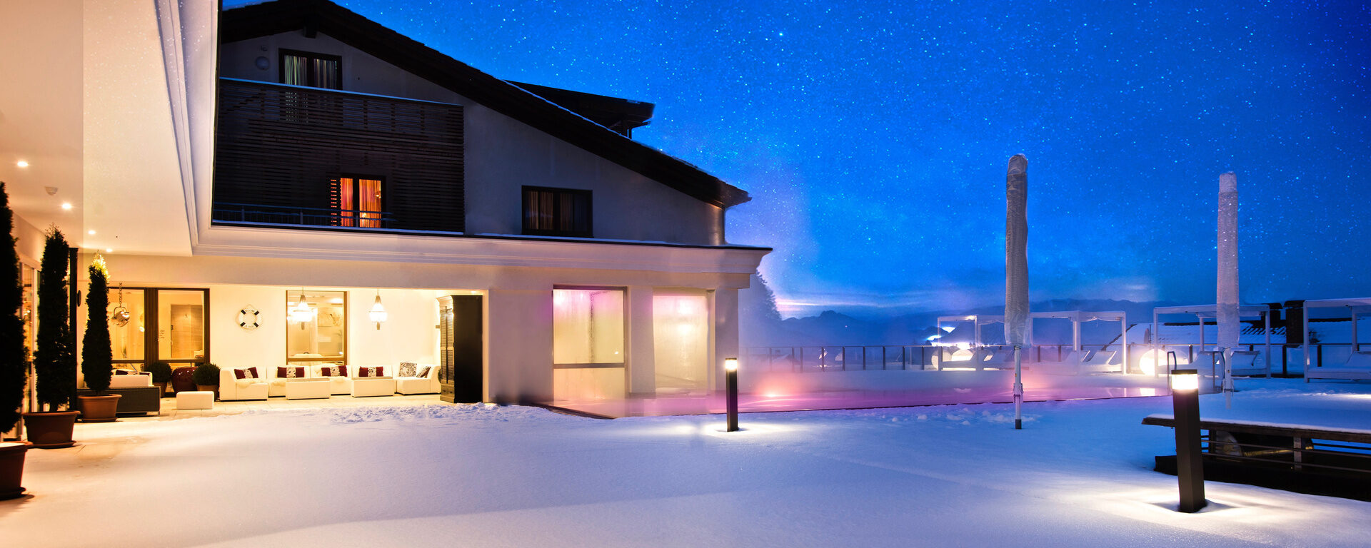 Das Wellnesshotel Oswald im Bayerischen Wald erstrahlt bei Nacht in märchenhaftem Winterambiente.