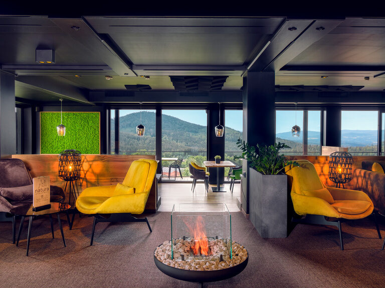 Die Lounge im Hotel Natura in Bodenmais mit große Fenster bieten einen atemberaubenden Blick auf die umliegende Landschaft des Bayerischen Waldes.