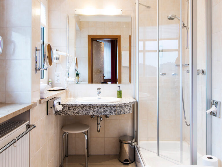 Helles, geräumiges Badezimmer im Hotel Oswald mit hochwertigen Amaturen.