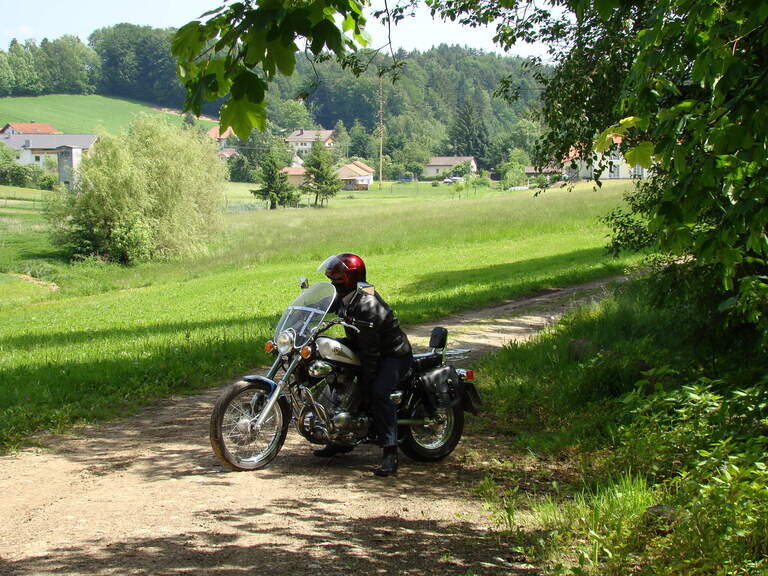 Ein Motorradfahrer macht eine Pause auf einem Feldweg im Bayerischen Wald.