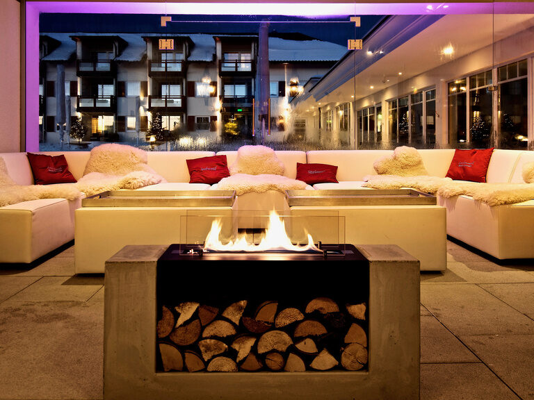 Gemütliche Outdoor-Lounge mit Feuerstelle im Hotel Oswald Bayerischer Wald bei Nacht.