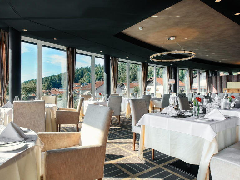 Helles, modernes Panoramarestaurant im Hotel Oswald mit großen Fensterfronten, stilvoll gedeckten Tischen und traumhaftem Ausblick in den Bayerischen Wald.