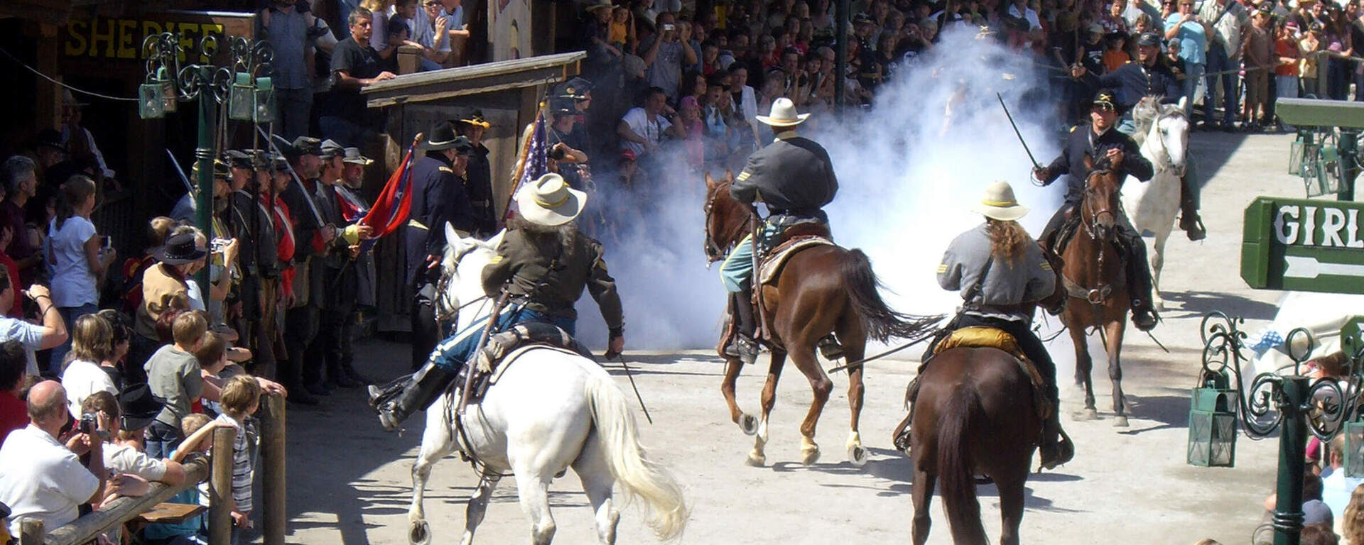Eine Gruppe reitet auf Pferden durch eine Straße in Pullman City Westernstadt im Bayerischen Wald.