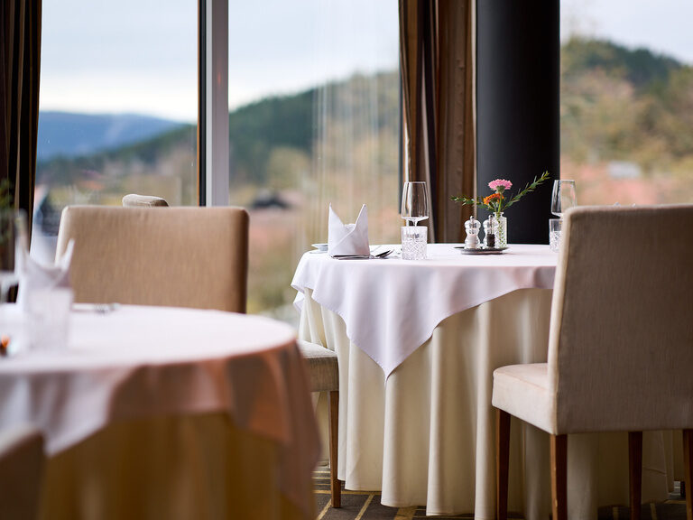 Elegant gedeckte Tische im Hotelrestaurant mit Panoramablick auf den Bayerischen Wald.