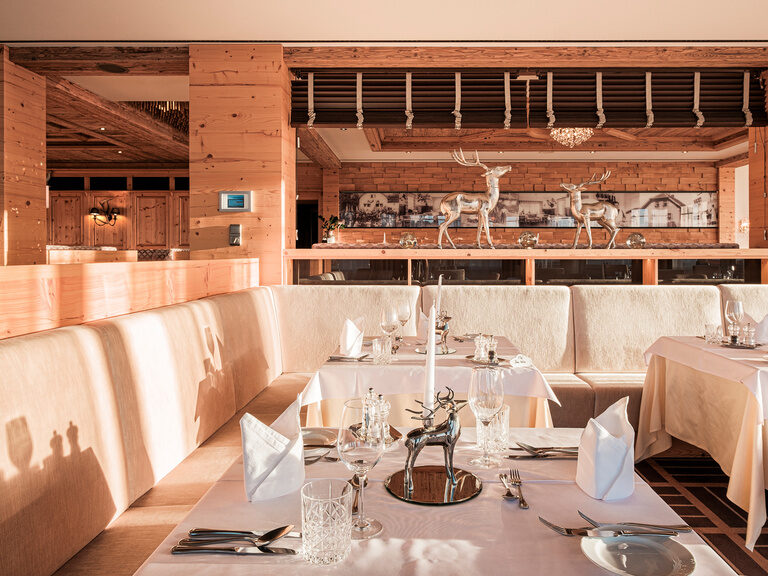 Das stilvoll gedeckte Restaurant im Landhausstil mit eleganter Hirsch-Dekoration und warmem Holzambiente im Hotel Oswald.