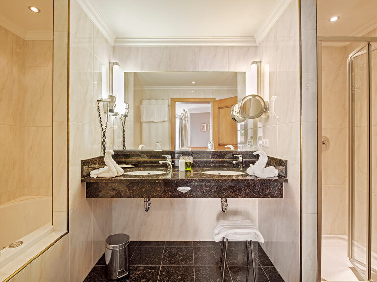 Das großzügige Badezimmer der Romantiksuite im Hotel Oswald mit Whirlpoolwanne, Doppelwaschbecken und Dusche.