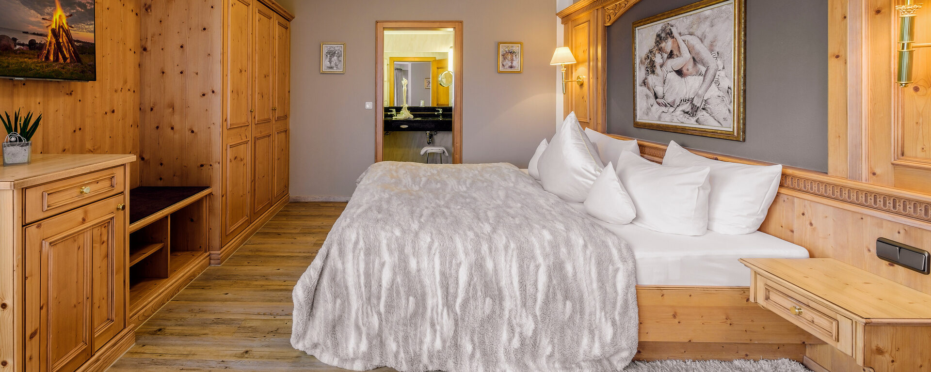 Das elegante Schlafzimmer der Romantiksuite im Wellnesshotel Oswald mit stilvollem Holzinterieur und Wohlfühlatmosphäre.
