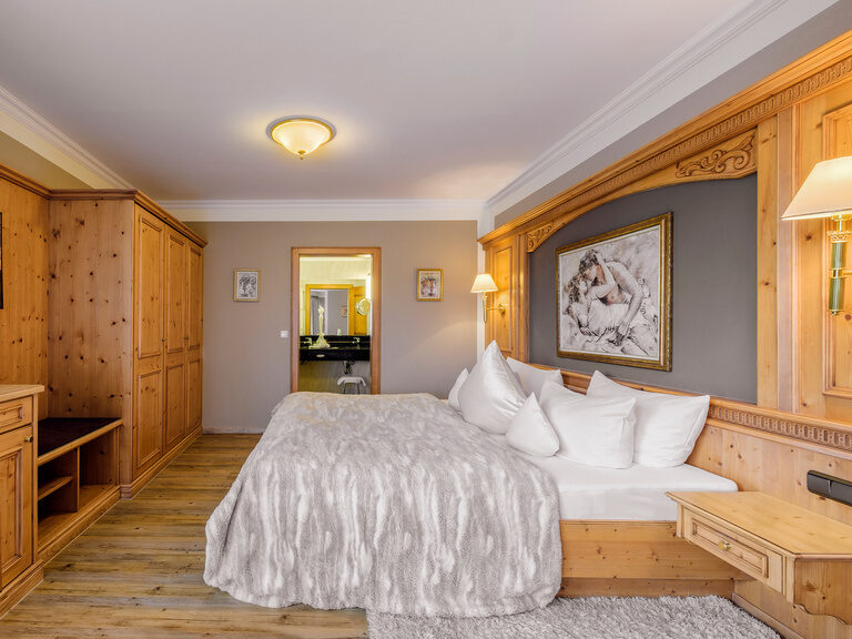 Das elegante Schlafzimmer der Romantiksuite im Wellnesshotel Oswald mit stilvollem Holzinterieur und Wohlfühlatmosphäre.