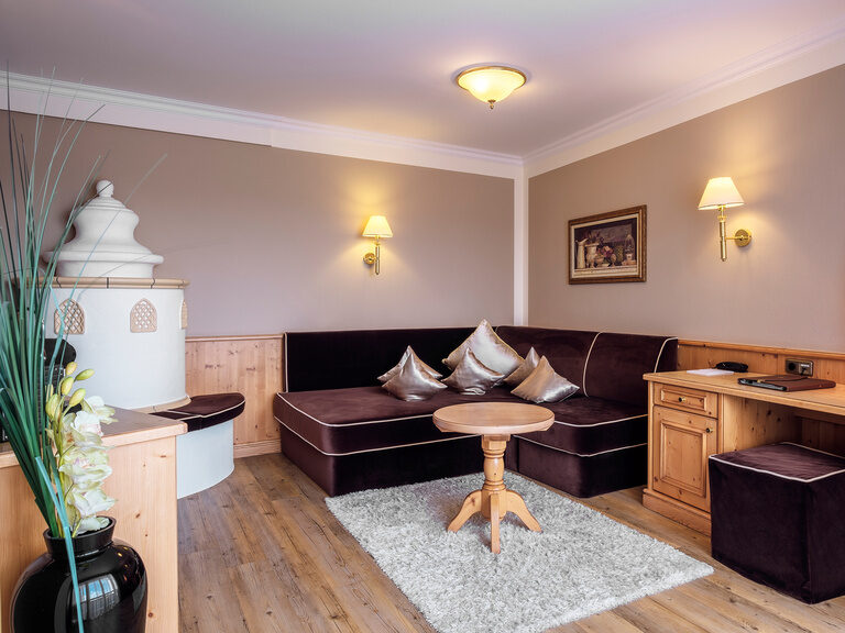 Der Wohnbereich der Romantiksuite im Hotel Oswald Bayerischer Wald mit gemütlicher Sitzecke, Kachelofen und Schreibtisch.