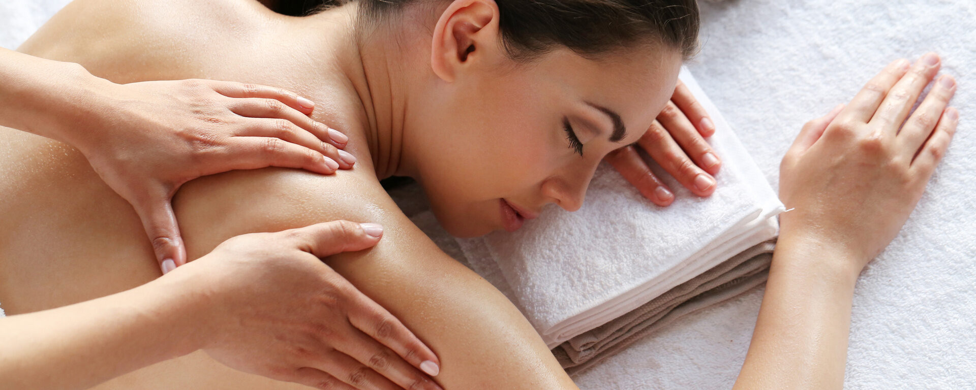 Frau entspannt auf einem weißen Handtuch während einer Massage im Wellnesshotel Oswald Bayerischer Wald