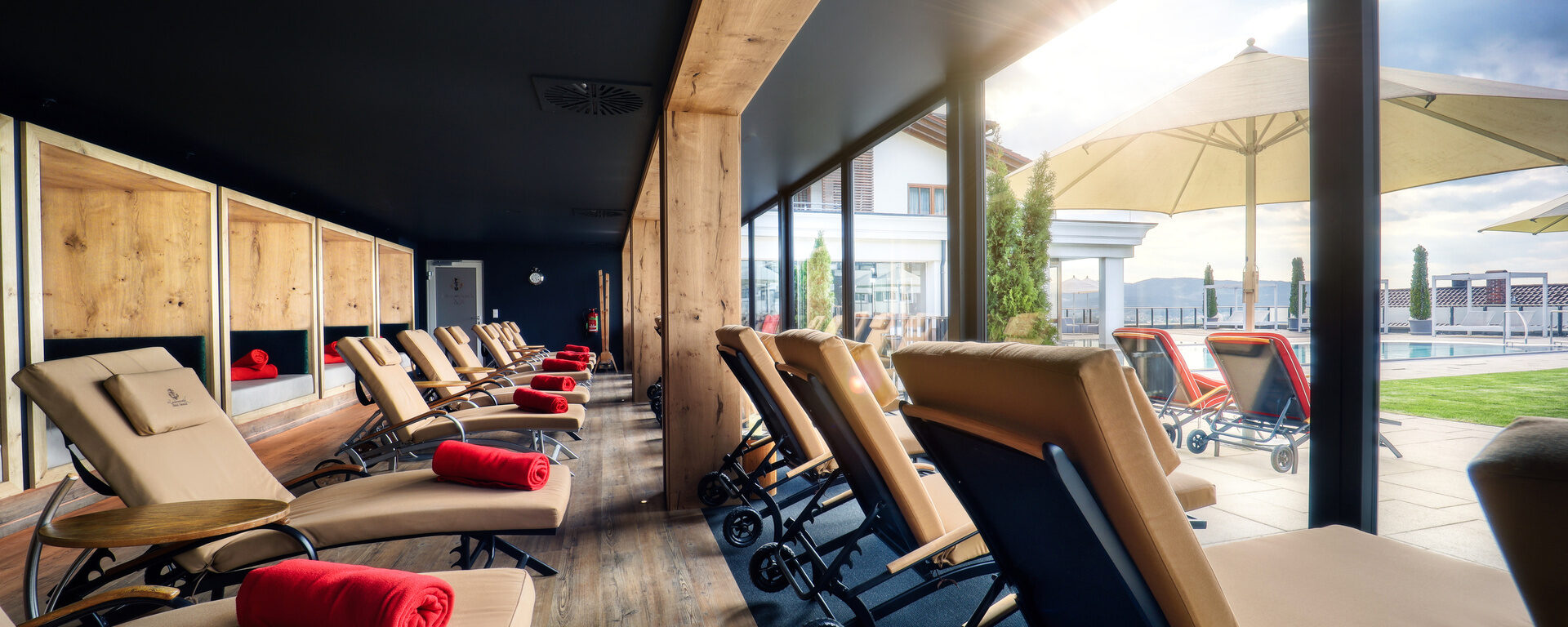 Der moderne Ruheraum mit verstellbaren Ruheliegen mit beigen Polstern und viel natürlichem Licht durch die Glasfront im Hotel Oswald.