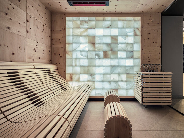 Salzgrotte im Hotel Oswald mit beleuchteter Salzsteinwand, ergonomischen Holzliegen und wohltuender Atmosphäre.