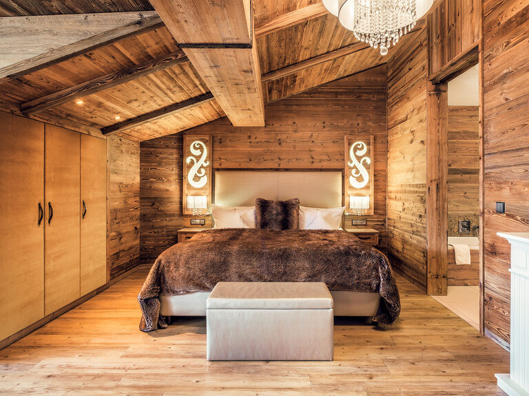 Ein großes Bett in einem Schlafzimmer mit Holzverkleidung im Landromantik Hotel Oswald.