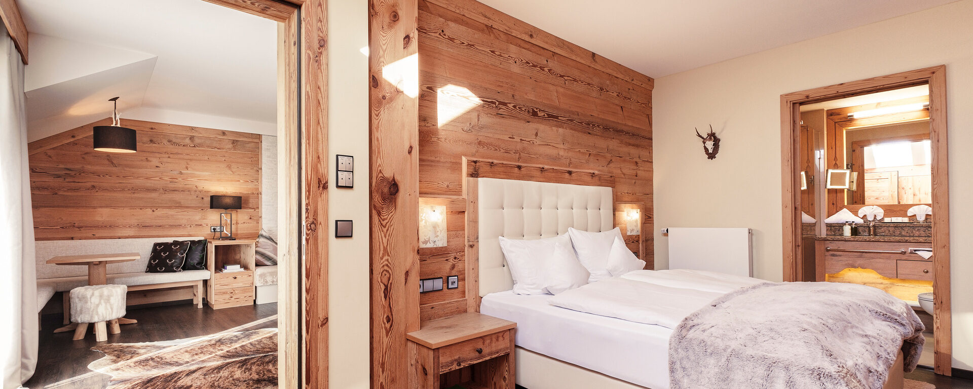 Das elegante Schlafzimmer der Top of Suite Jagasitz Plus mit direktem Blick in den gemütlichen Wohnbereich des Hotel Oswald im Bayerischen Wald.