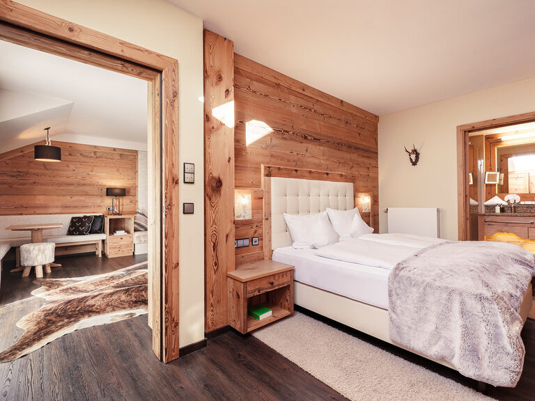 Das elegante Schlafzimmer der Top of Suite Jagasitz Plus mit direktem Blick in den gemütlichen Wohnbereich des Hotel Oswald im Bayerischen Wald.