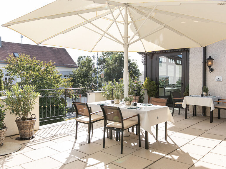 Sonnenterrasse mit gedecktem Tisch und Sonnenschirm im Hotel Oswald im Bayerischen Wald.