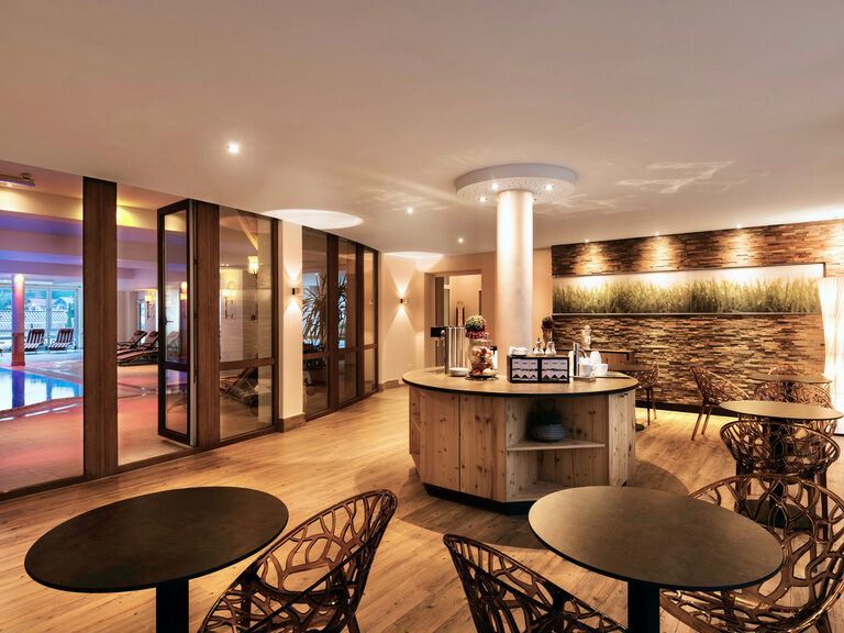 Holz- und Steinelemente, gemütliche Sitzmöglichkeiten und eine Teebar laden zu einer entspannten Pause im Wellnessbereich Hotel Oswald ein.