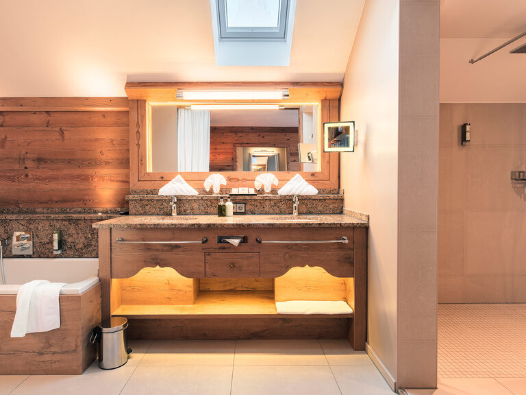 Das stilvolle Badezimmer der Top of Suite Jagasitz Plus im Wellnesshotel Oswald im Bayerischen Wald mit edlem Doppelwaschbecken, Naturstein und Oberlicht.