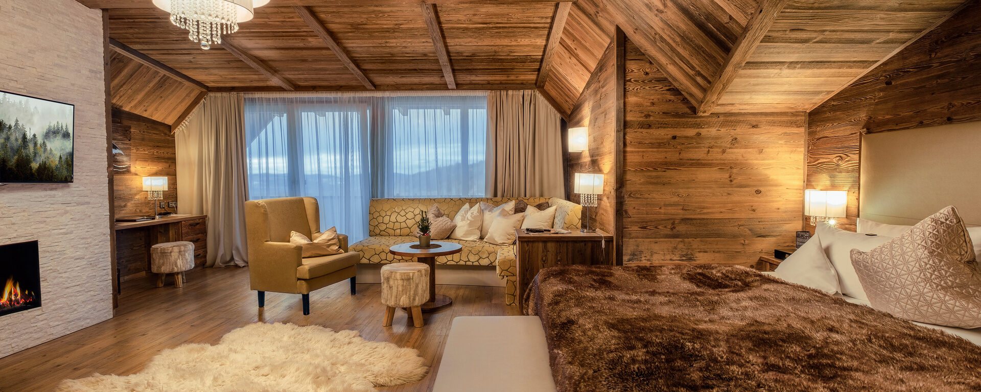 Die exklusive Suite Storchennest im Hotel Oswald mit gemütlichem Chalet-Ambiente, edler Holzverkleidung, Kamin und Panoramafenster.