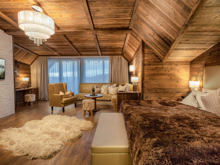 Die exklusive Suite Storchennest im Hotel Oswald mit gemütlichem Chalet-Ambiente, edler Holzverkleidung, Kamin und Panoramafenster.