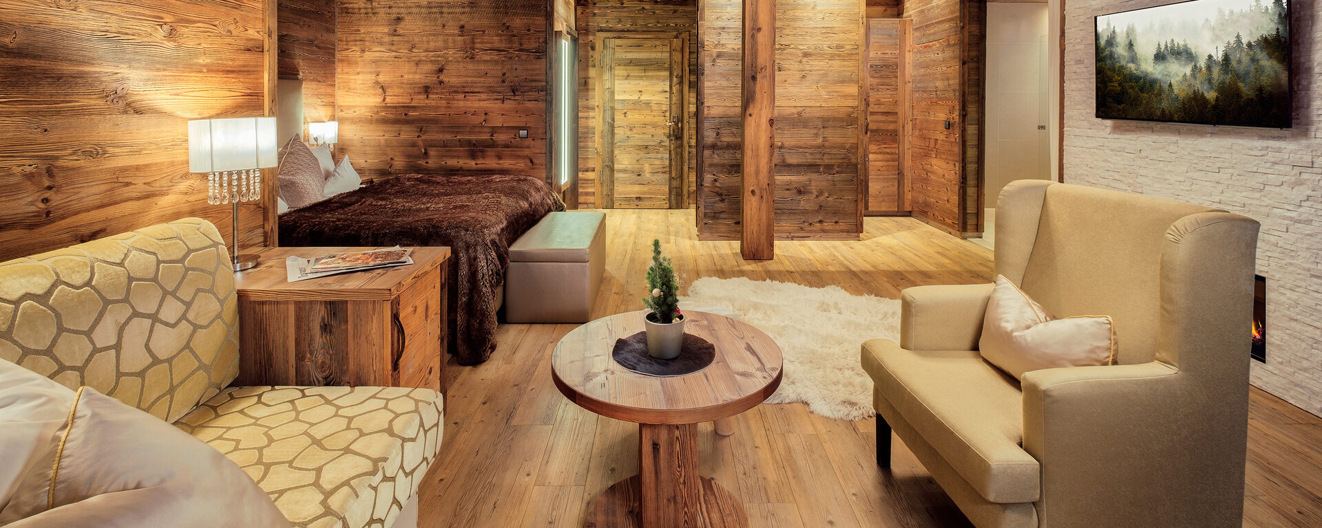 Die Top of Suite Storchennest im Hotel Oswald mit edle Holzelemente, stilvolle Beleuchtung und eine gemütliche Sitzecke.