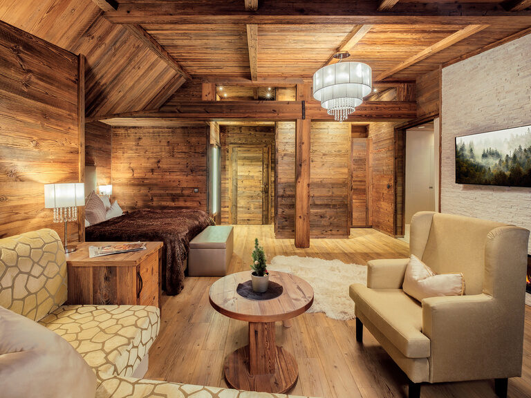 Die Top of Suite Storchennest im Hotel Oswald mit edle Holzelemente, stilvolle Beleuchtung und eine gemütliche Sitzecke.