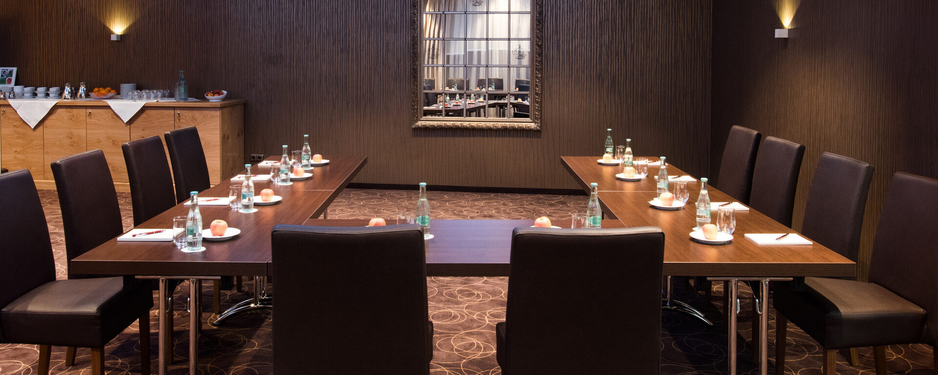 Der Meetingraum im Hotel Oswald mit stilvollem Ambiente, dunklen Holztischen und bequemen Stühlen für produktive Besprechungen im Bayerischen Wald.